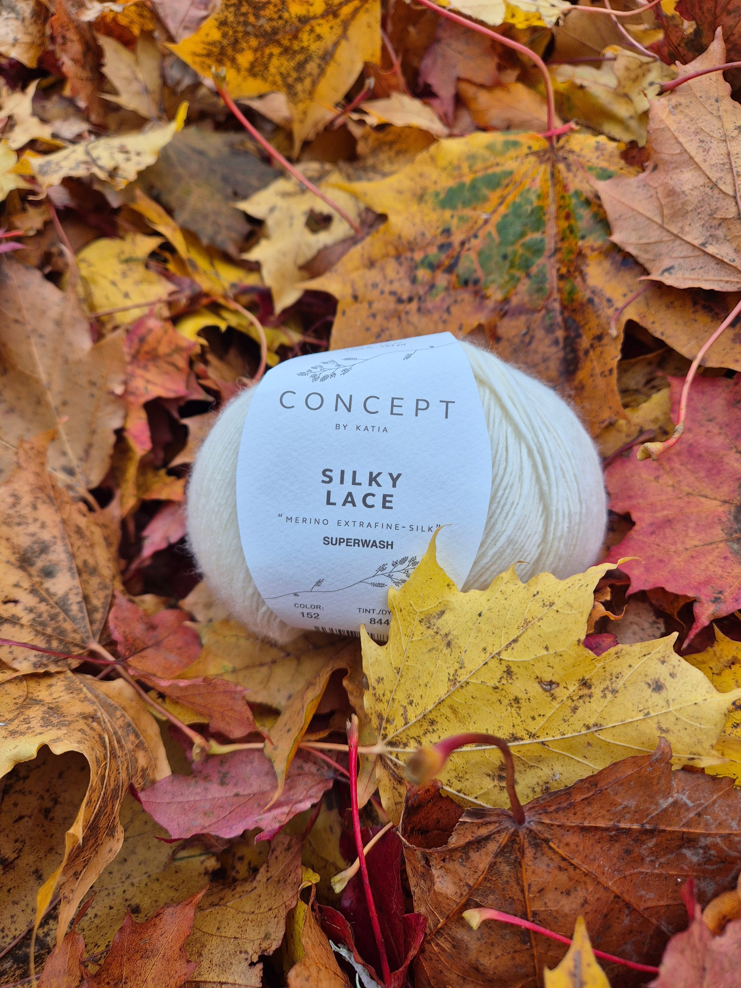 Nystan Katia Silky Lace i ljus merinoull ligger bland färgglada höstlöv – inspirerande bild för stickning och garn från Garnverkstan.