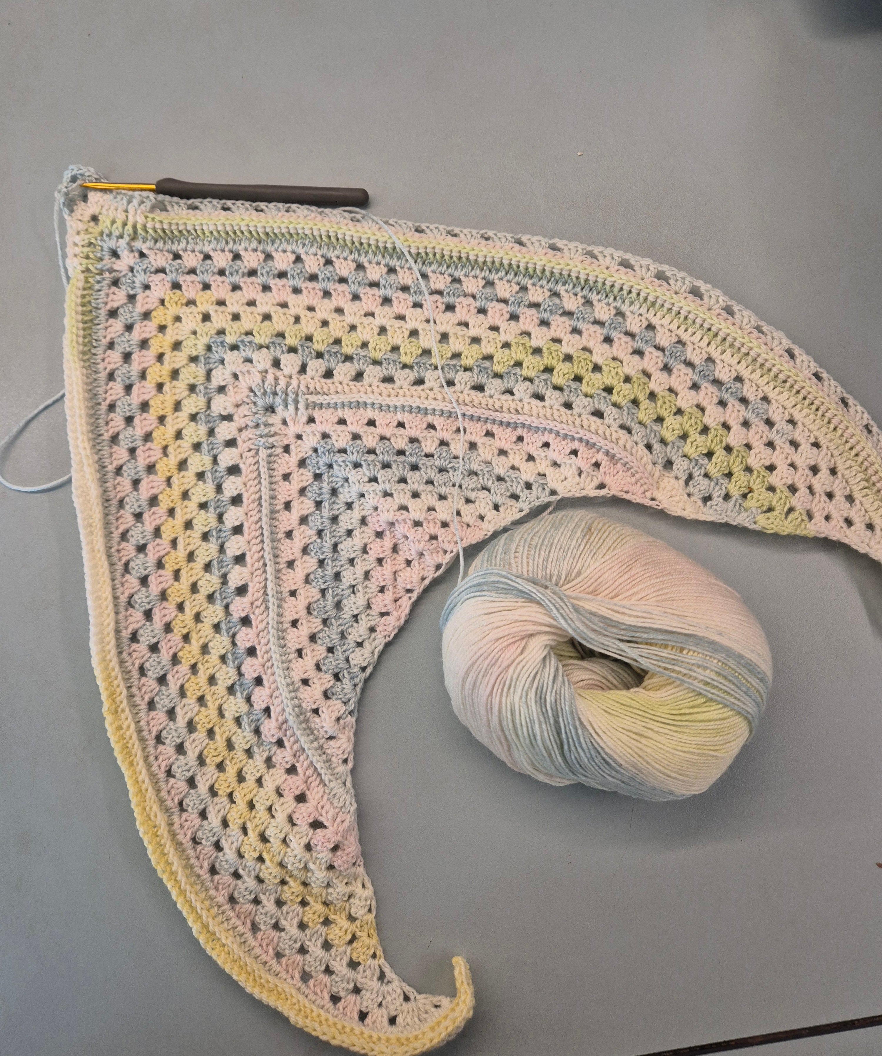 Pågående stickprojekt i pastellfärger med garnnystan bredvid – exempel på nybörjarstickning med material från Garnverkstan.